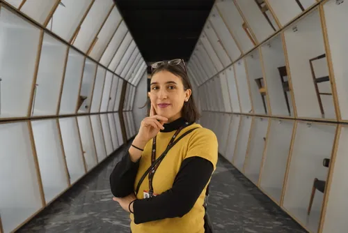 Donna in maglione giallo in un corridoio museale curvo e luminoso