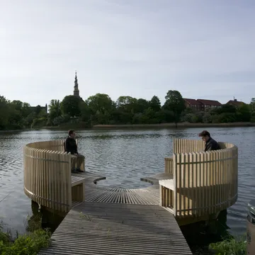 Pontile circolare in legno su un lago con guglia di chiesa lontana